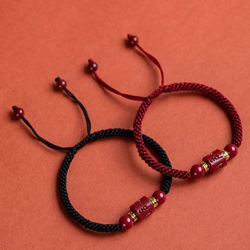 Om Mani Padme Hum cinnabar bracelet detail shot displaying gold-plated metal spacers, polished beads, and sacred Sanskrit engraving
