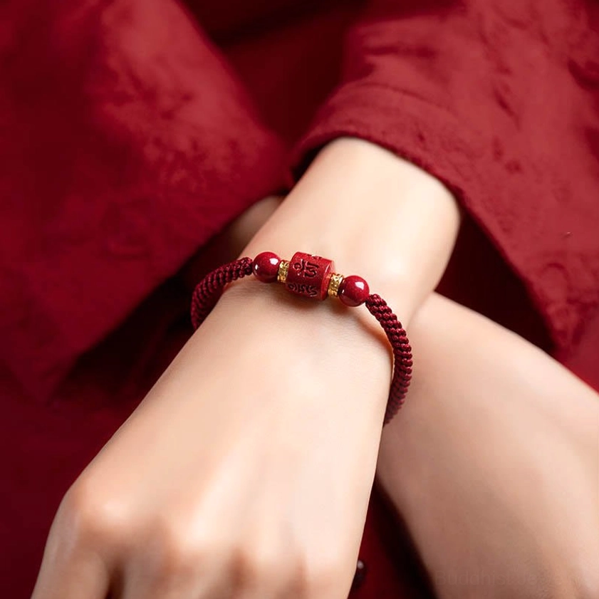 Om Mani Padme Hum cinnabar bracelet worn on wrist with red traditional clothing, showing elegant fit and daily wear style