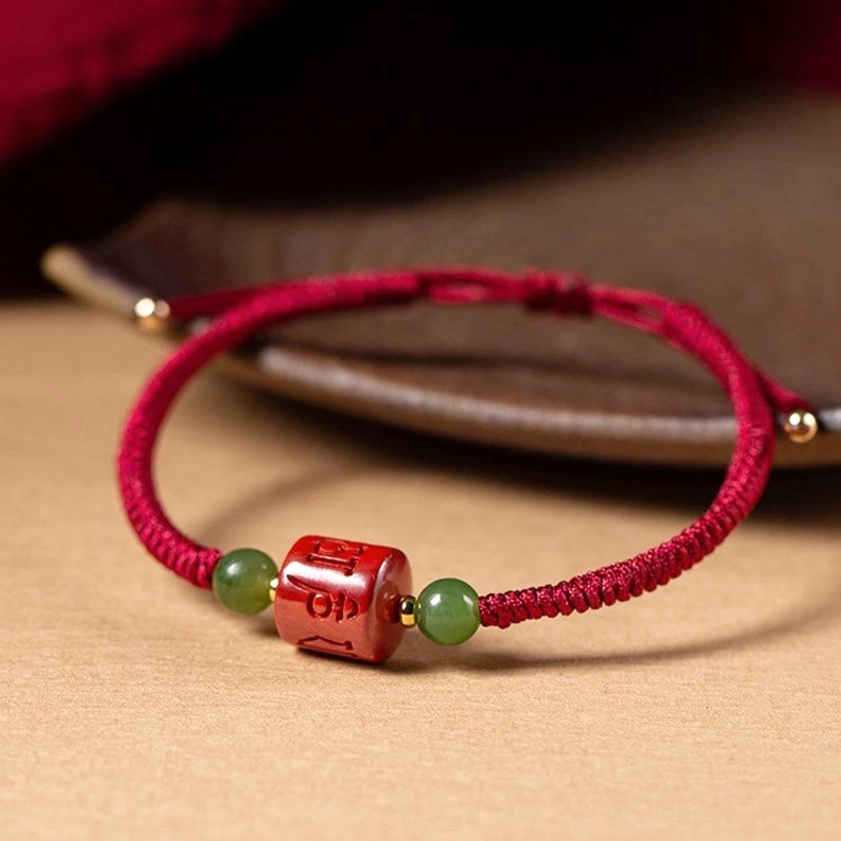 Close-up detail of engraved Om Mani Padme Hum six-syllable mantra on cinnabar bead, high-resolution view