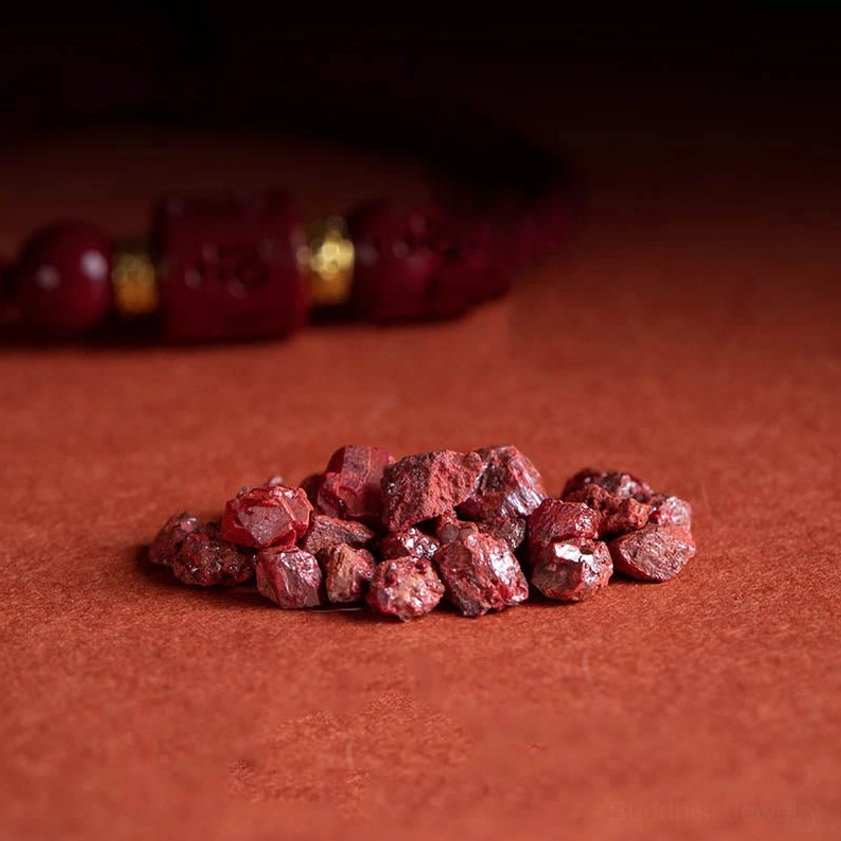 Natural raw cinnabar ore specimens displayed alongside finished Om Mani Padme Hum Buddhist bracelet showing material source