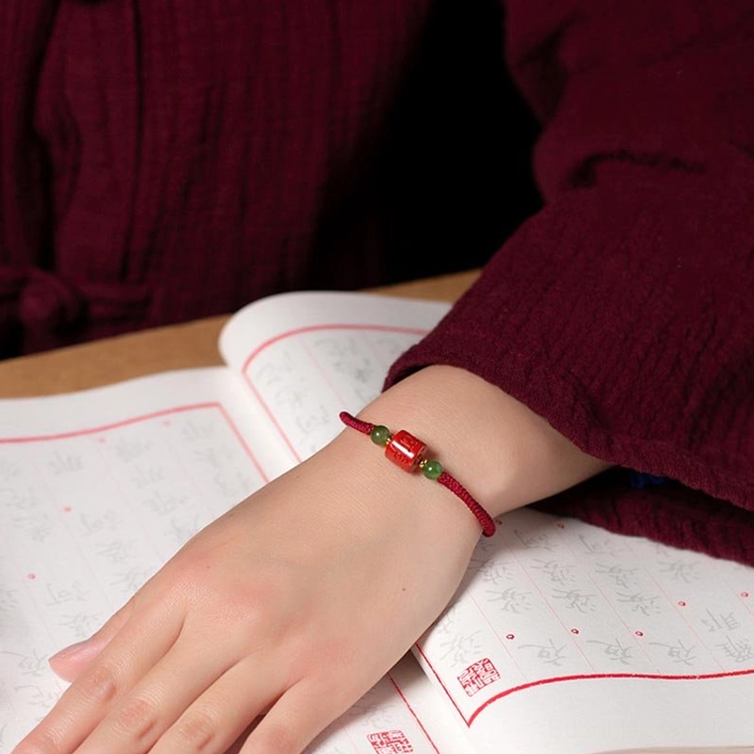 Red braided rope Om Mani Padme Hum cinnabar bracelet with jade accents, showing traditional Buddhist craftsmanship
