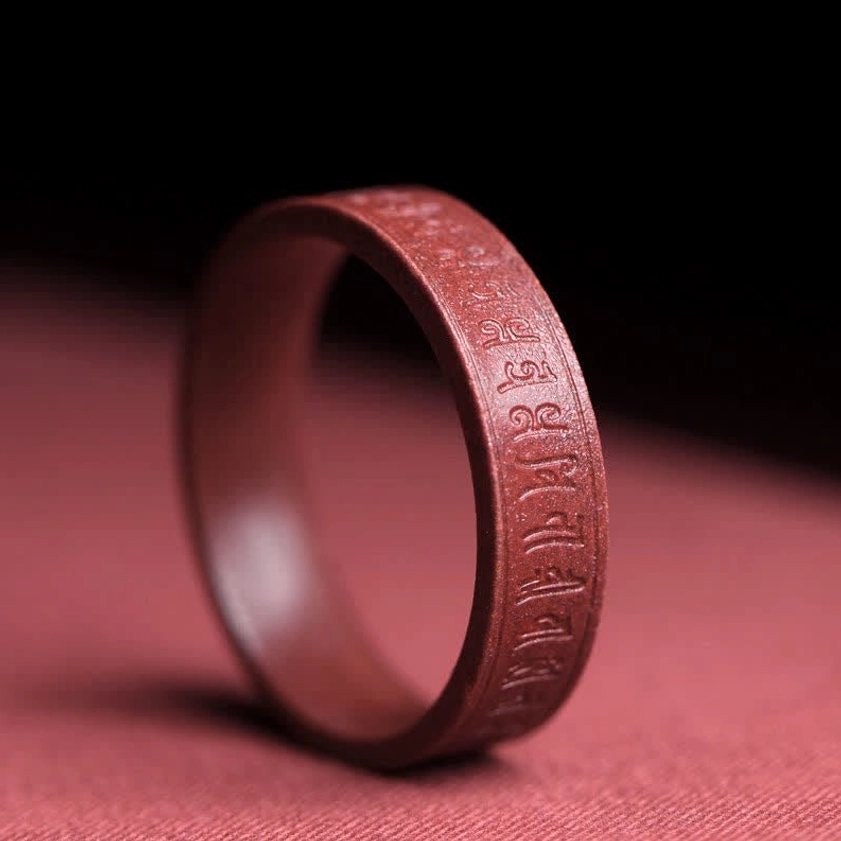 Side close-up of Om Mani Padme Hum mantra carved cinnabar ring showing intricate Buddhist mantra engravings and craftsmanship