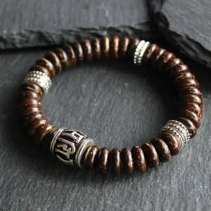 Brown coconut shell Om Mani Padme Hum bracelet with engraved silver mantra beads, flat lay view on dark slate