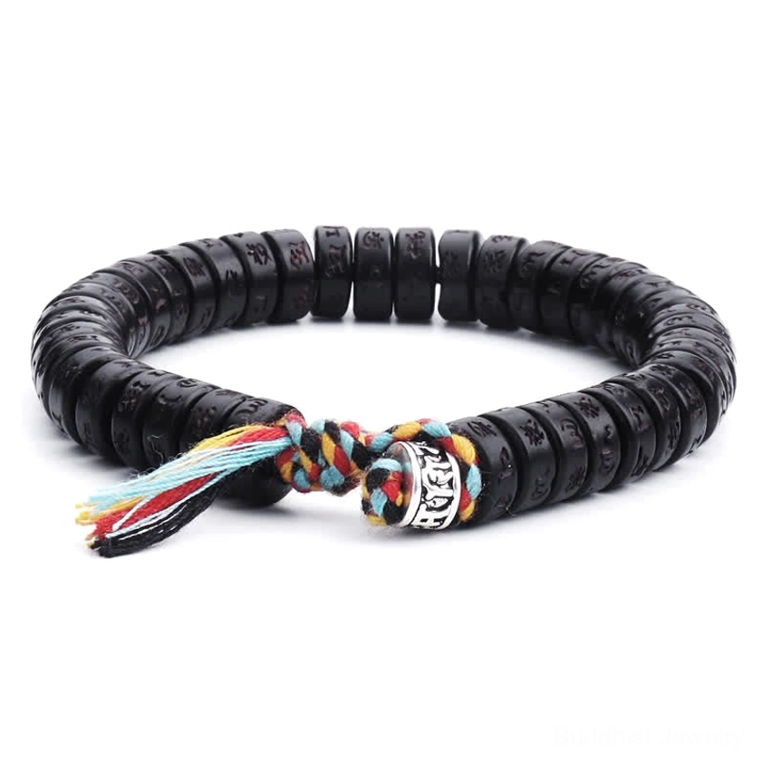 Om Mani Padme Hum engraved coconut shell bracelet with black beads and colorful woven tassel clasp, overhead flat lay view