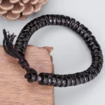 Om Mani Padme Hum coconut shell bracelet side view with natural wooden and pine cone styling
