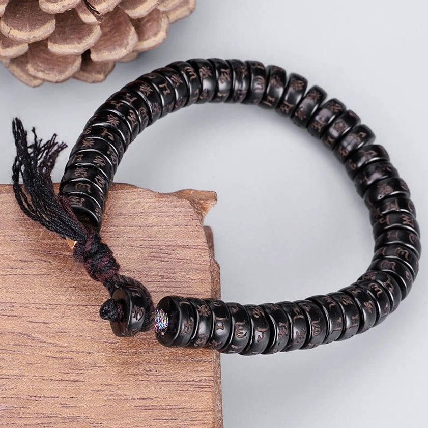 Om Mani Padme Hum coconut shell bracelet side view with natural wooden and pine cone styling