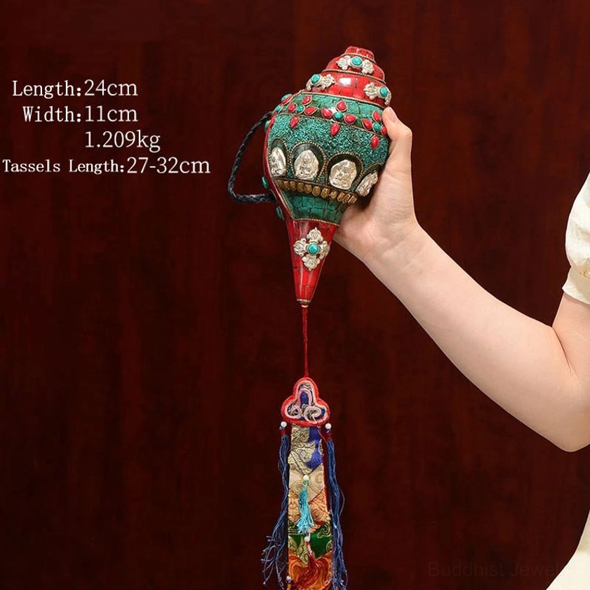 Tibetan Buddhist conch shell decoration with Om Mani Padme Hum symbols held in hand showing detailed silver Buddha medallions and gemstone accents