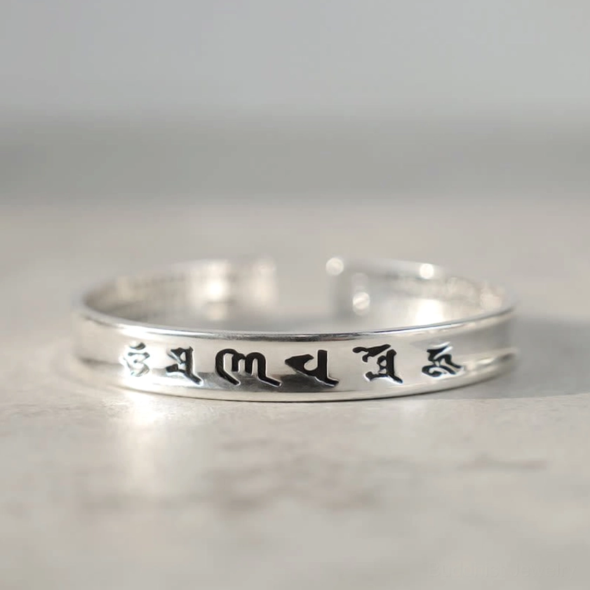 Sacred mantra copper bracelet low-angle front view with polished silver-toned finish and bright reflective surface