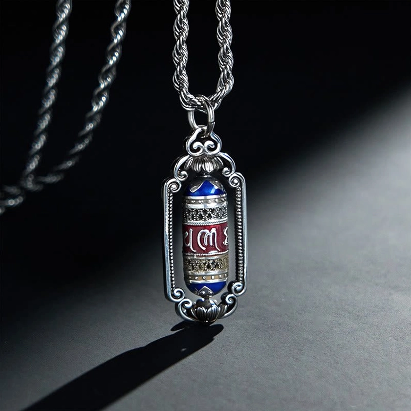 Om Mani Padme Hum copper prayer wheel pendant necklace with silver vintage frame, front close-up view with dramatic studio lighting