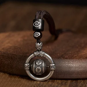 Om Mani Padme Hum rotating copper pendant necklace with cloud pattern details, top-down view showing vintage silver tone finish