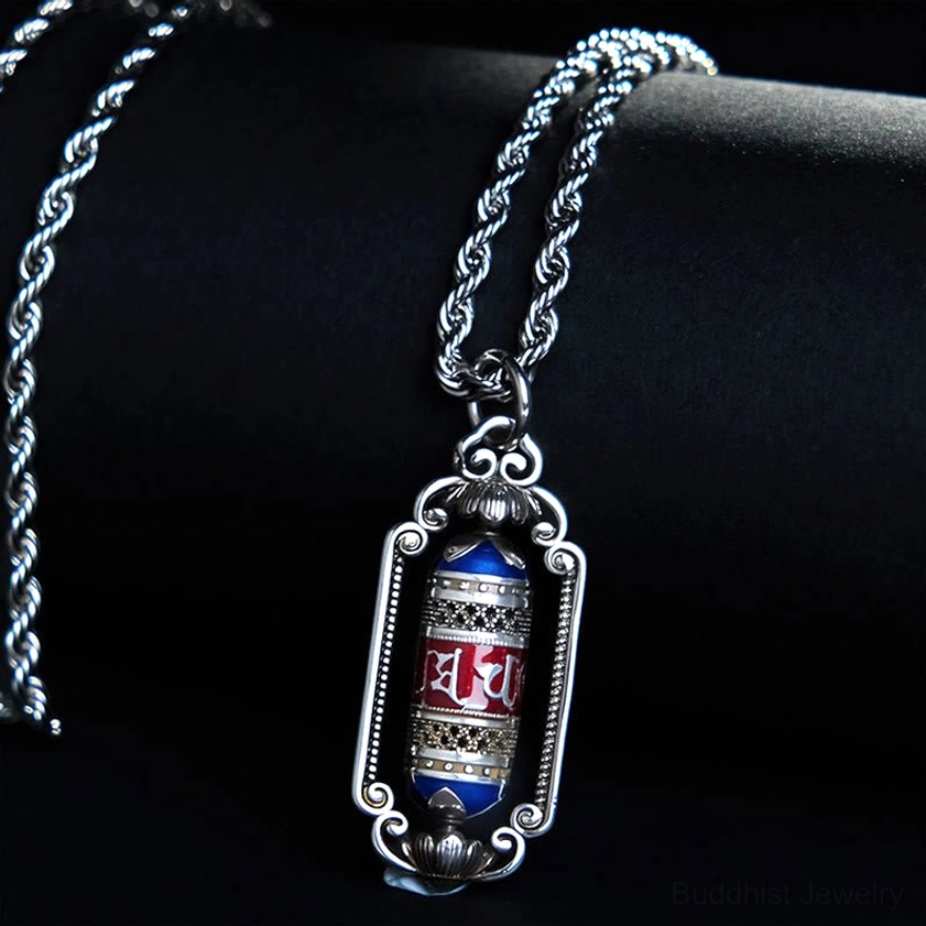 Buddhist prayer wheel copper pendant side view showing red and blue enamel mantra details with silver ornate frame