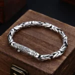 Om Mani Padme Hum Dorje Vajra copper bracelet with engraved mantra charm, displayed on wooden jewelry stand