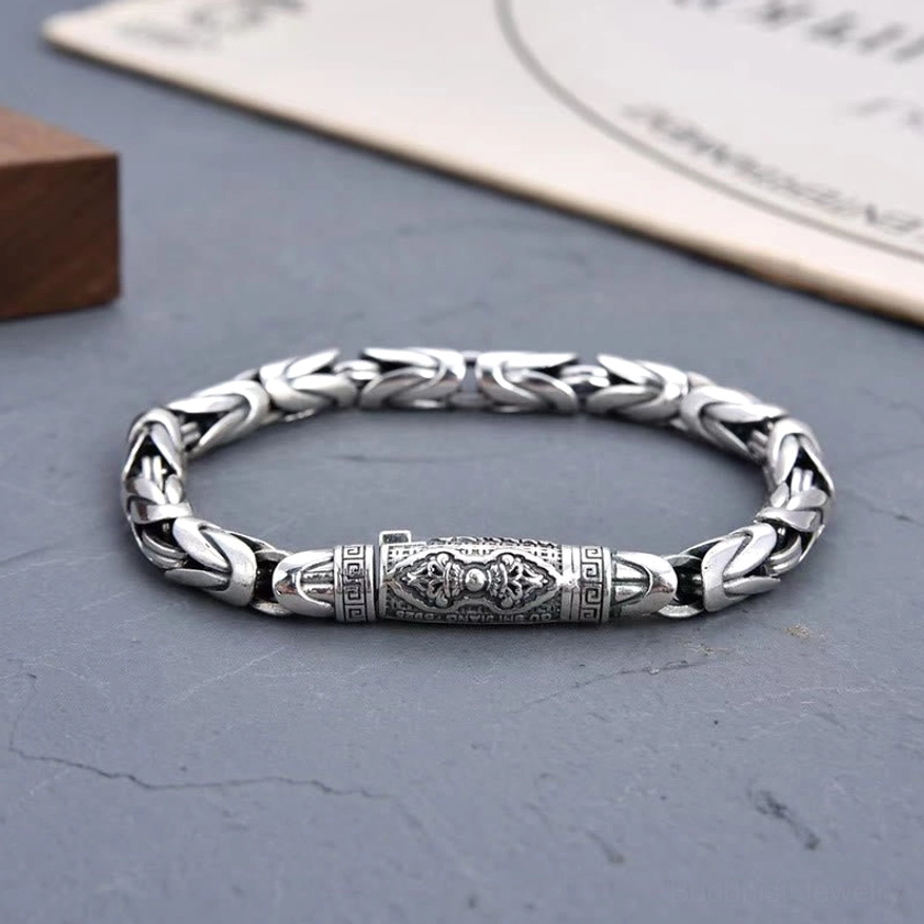 Complete circular Om Mani Padme Hum Dorje Vajra copper bracelet with engraved central mantra charm displayed on grey surface