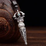 Rotatable Om Mani Padme Hum Dorje Vajra pendant necklace with turquoise inlays and carved Buddhist scriptures, displayed on wooden craft background