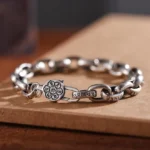 Om Mani Padme Hum Double Dorje copper bracelet with engraved mantra links and premium buckle clasp, side view on wooden board