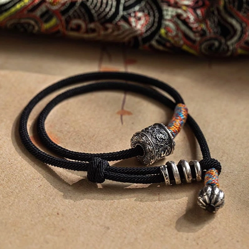 Handcrafted Buddhist bracelet showing dual wrap design with black braided cord and multicolor woven elements