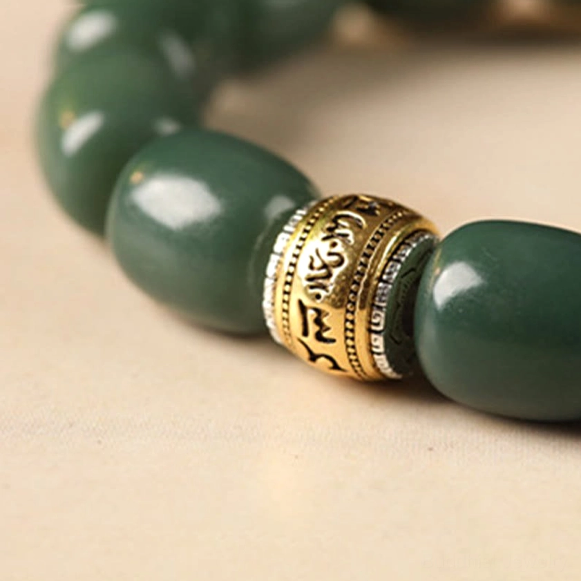Close-up detail of engraved om mani padme hum metal spacer on bodhi seed bracelet