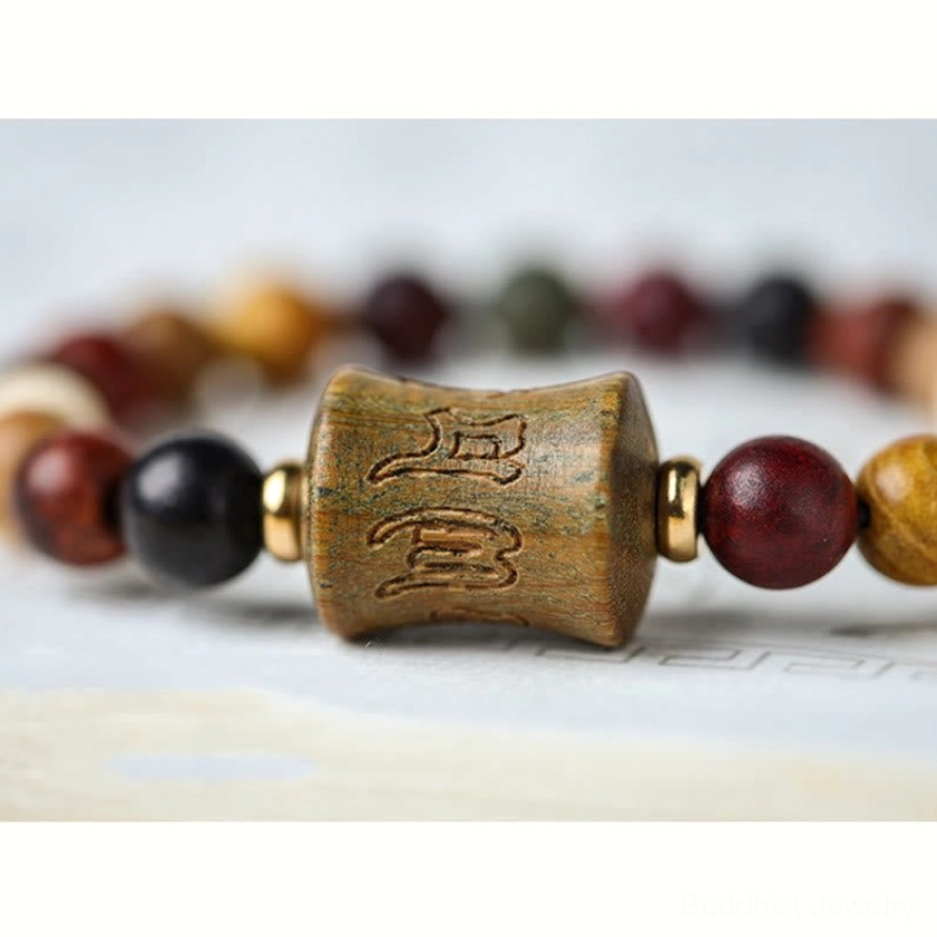 Macro close-up of Om Mani Padme Hum carved wooden focal bead with copper spacers and surrounding prayer beads
