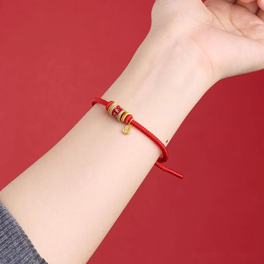 Red string Buddhist bracelet worn on wrist showing mantra beads and Fu charm in daily wear style