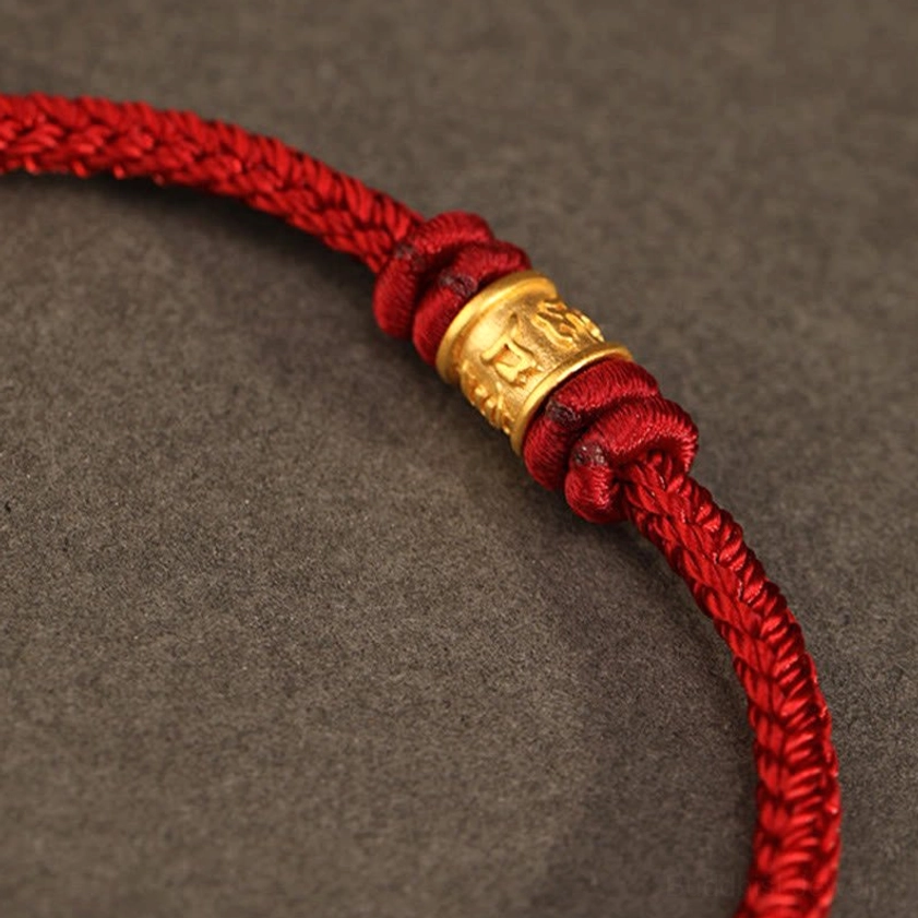 Close-up detail of engraved 999 gold bead with Om Mani Padme Hum mantra, side angle view