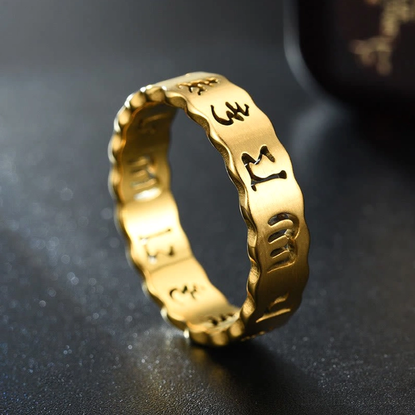 Close up detail of golden om mani padme hum spinning ring showing clear engraved tibetan text and polished finish