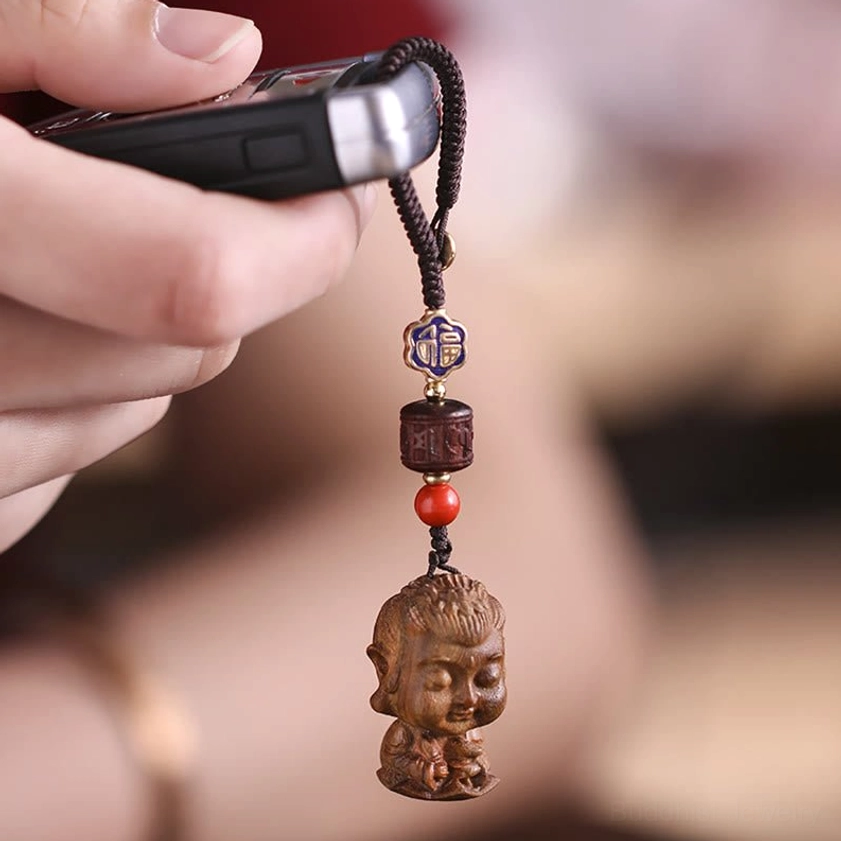 Om Mani Padme Hum sandalwood keychain held in palm showing size reference and portable spiritual accessory