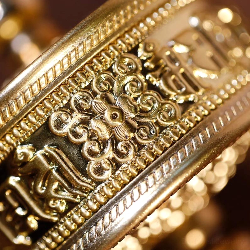 Macro close-up of Buddhist prayer wheel engraved script and motifs, polished golden metal texture, showing the om mani padme hum mantra inscriptions