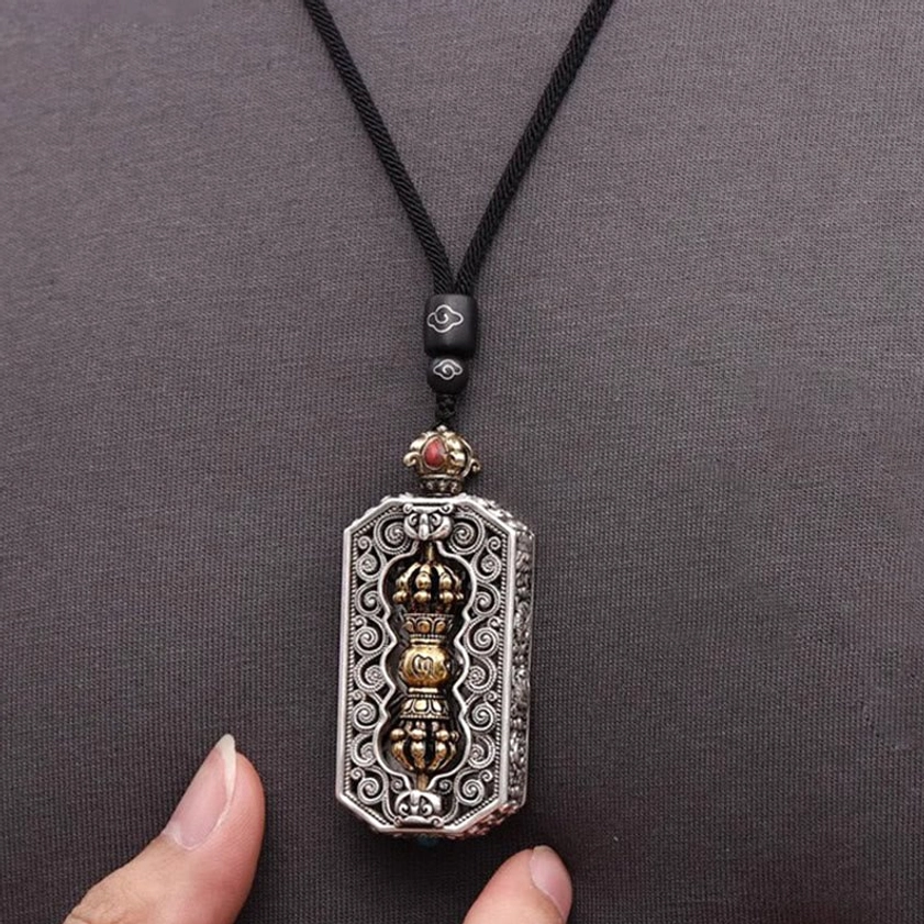 Buddhist om mani padme hum pendant on black braided necklace cord with filigree carved frame and rotatable dorje