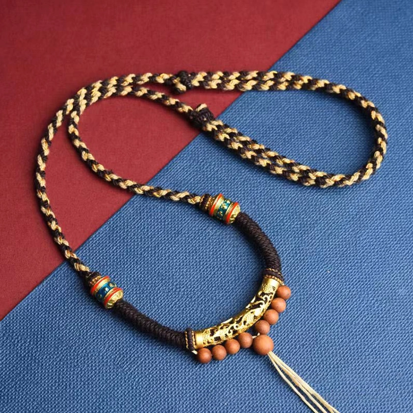 Handmade Buddhist prayer necklace showing two-tone braided rope detail with carved gold accents overhead view