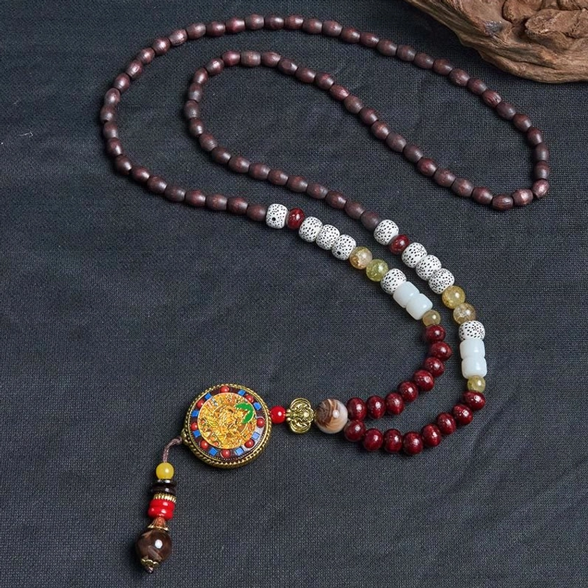 Buddhist prayer bead necklace detail showing mixed spacer beads, copper accents, and deity pendant with tassel