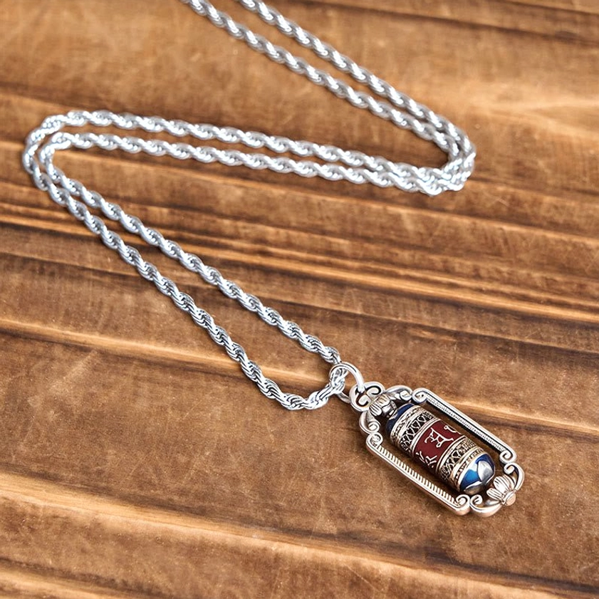 Om Mani Padme Hum copper prayer wheel necklace flat lay top-down view on wooden surface with twisted rope chain
