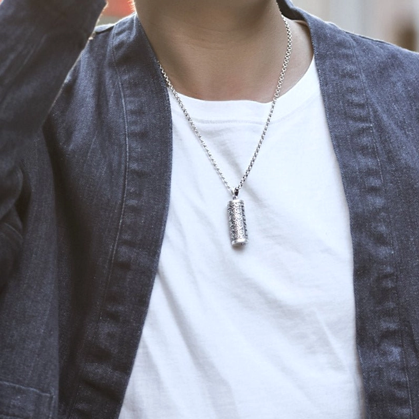 Buddhist mantra necklace worn on neck with casual street outfit - showing slim silver chain and compact pendant at collarbone