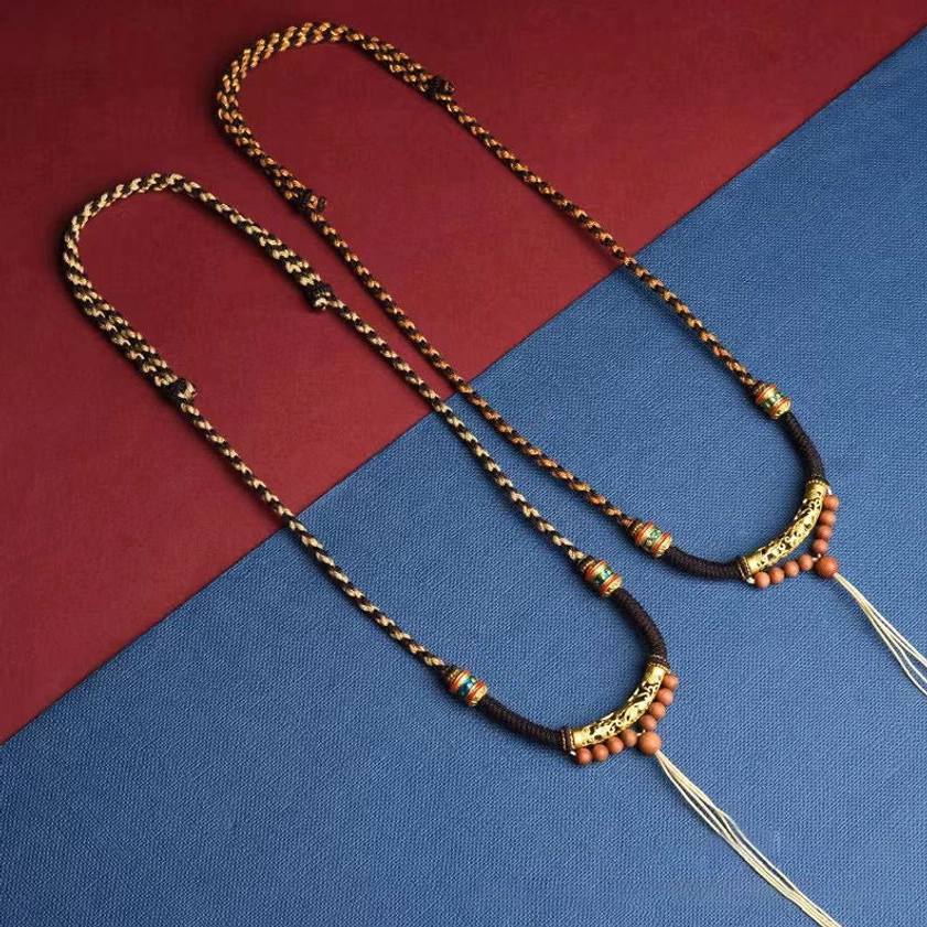 Two matching Om Mani Padme Hum Buddhist necklaces with tasseled ends and enamel decorated beads displayed flat lay