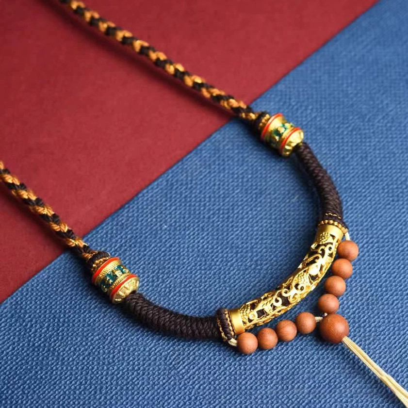 Close-up of Om Mani Padme Hum Buddhist necklace pendant with curved gold carved bead and enamel ring bead details