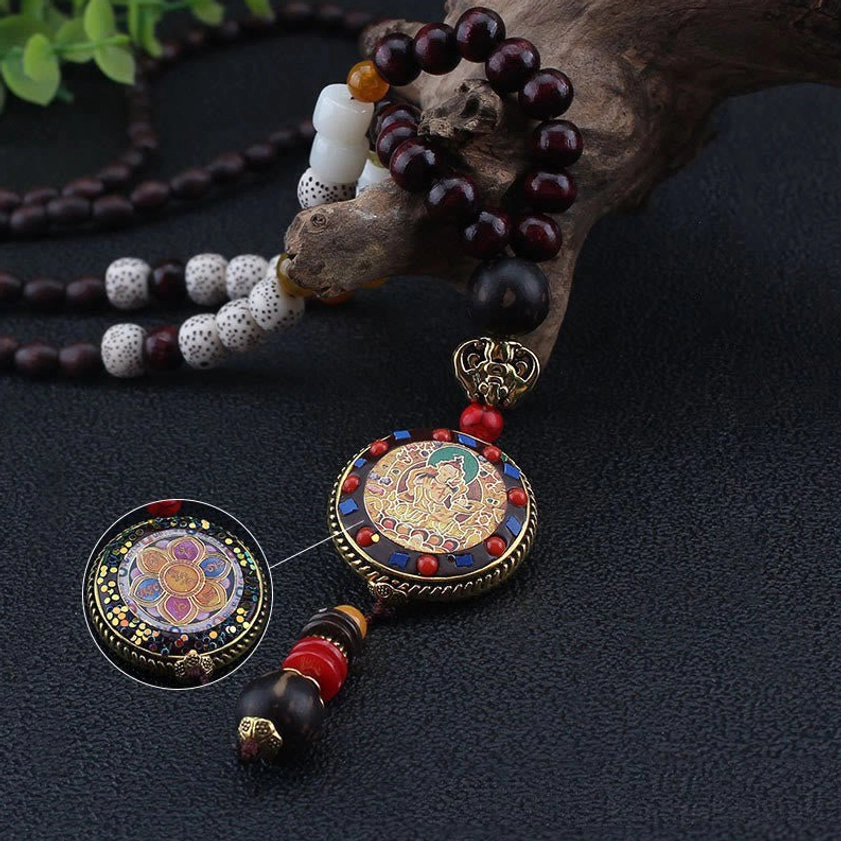 Close-up of enamel deity pendant charm on Buddhist wood bead mala necklace