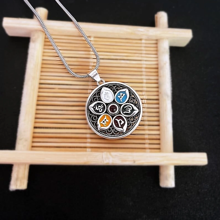 Om Mani Padme Hum mantra pendant displayed on bamboo stand showing full front design with enamel inlays