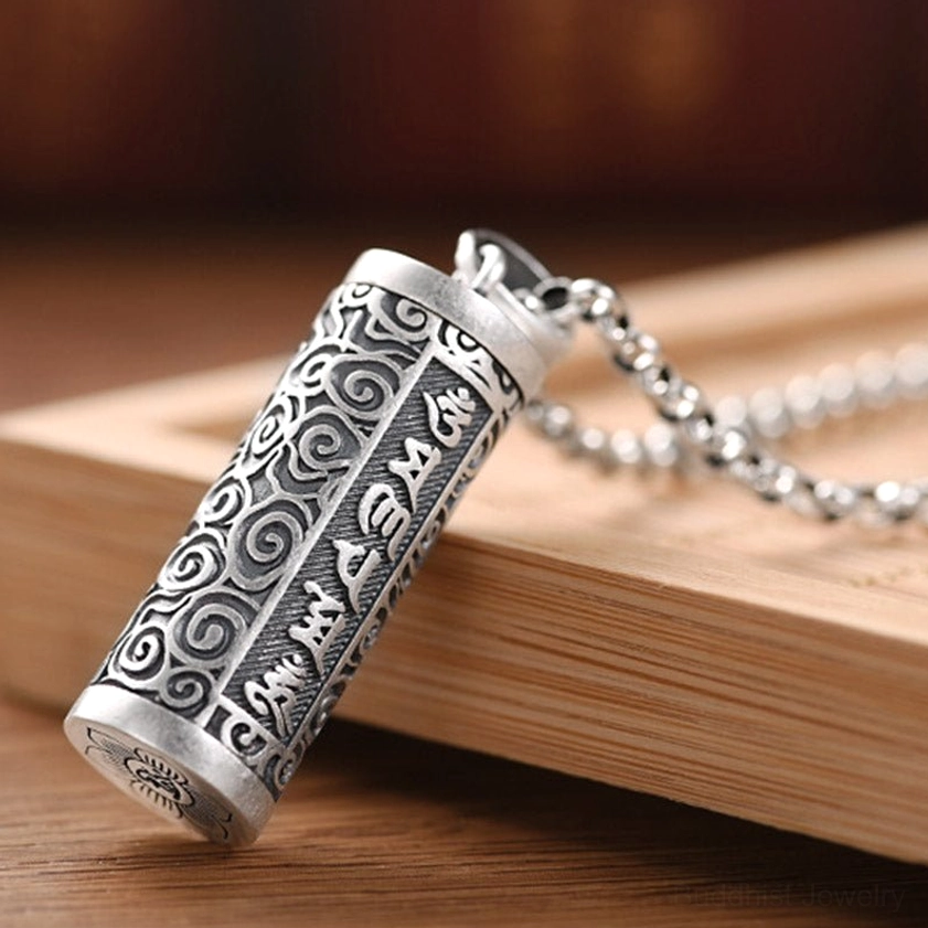 Om Mani Padme Hum cylinder pendant close-up showing embossed cloud patterns and Sanskrit mantras with silver chain attachment