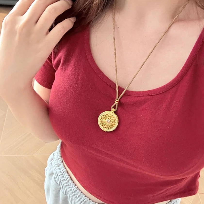 Wearable Om Mani Padme Hum pendant necklace worn at collarbone on person wearing red top, showing actual size and wearing position