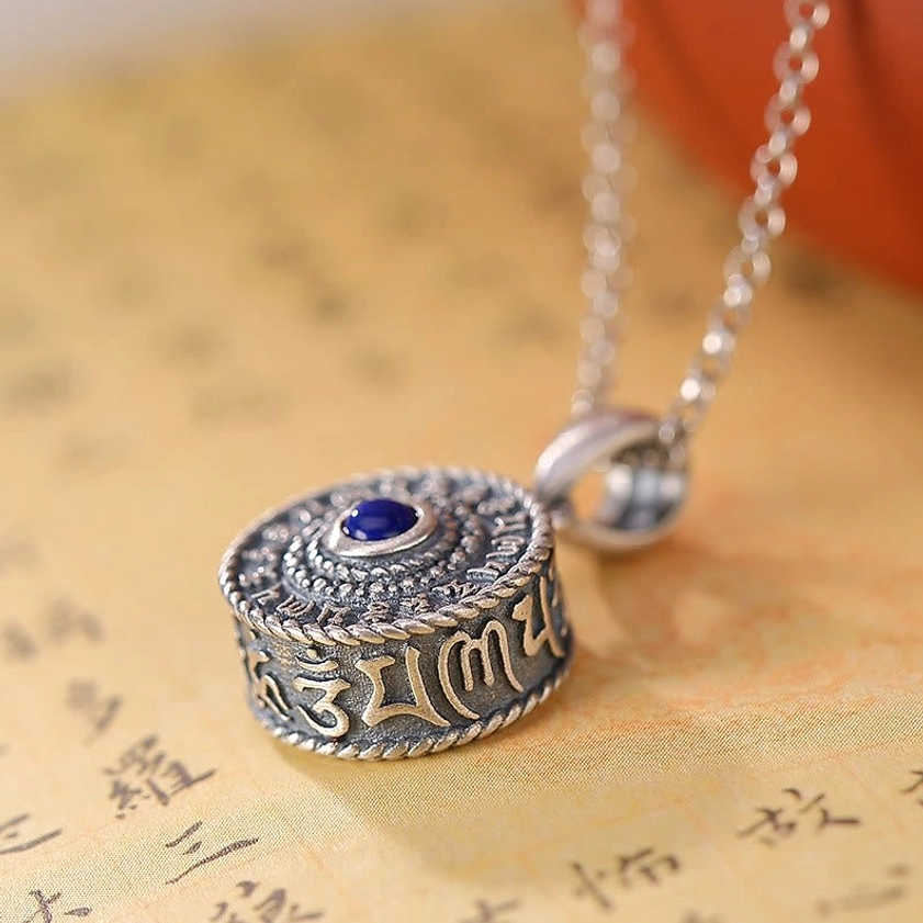 Side profile of cylindrical Om Mani Padme Hum sterling silver pendant showing engraved mantra letters and lapis lazuli inlay with attached silver chain