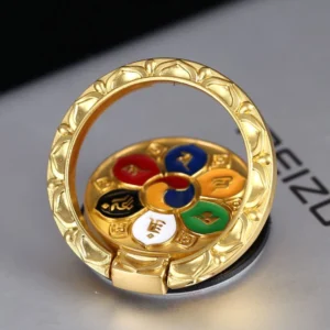 Om Mani Padme Hum gold-plated phone ring holder with lotus embossed design, displayed on desk showing six-syllable mantra enamel craft