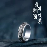 Om Mani Padme Hum PiXiu rotatable buddhist ring side profile view with antique silver finish and engraved mantras on dark stone background