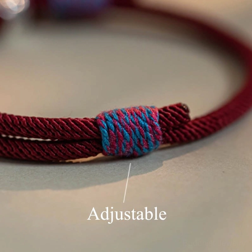 Buddhist prayer bracelet featuring sacred mantra bead and persimmon charm on adjustable braided cord