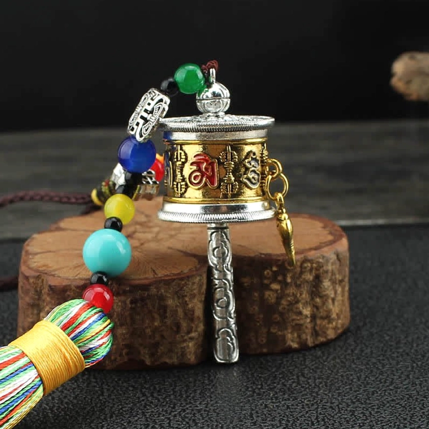 Gold-toned engraved Om Mani Padme Hum prayer wheel with turquoise bead accents close-up