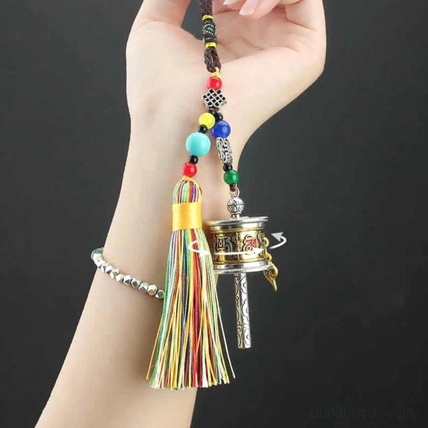 Om Mani Padme Hum prayer wheel held in hand showing portable size and rainbow tassel design