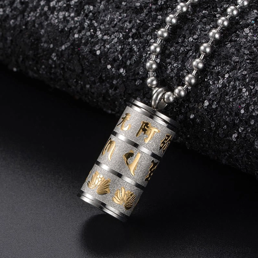 Om Mani Padme Hum cylindrical prayer wheel pendant featuring screw-on cap design, multiple finish layers, and detailed hand-engraved Sanskrit and lotus motif on dark background