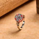 Om Mani Padme Hum rotatable copper prayer wheel ring with red enamel, front overhead view showing engraved mantra and crystal inlays