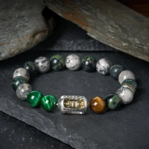 Om Mani Padme Hum protection bracelet with mixed natural stone beads including grey jasper, tiger eye, and green tiger eye with engraved Buddhist mantra metal charm on dark background