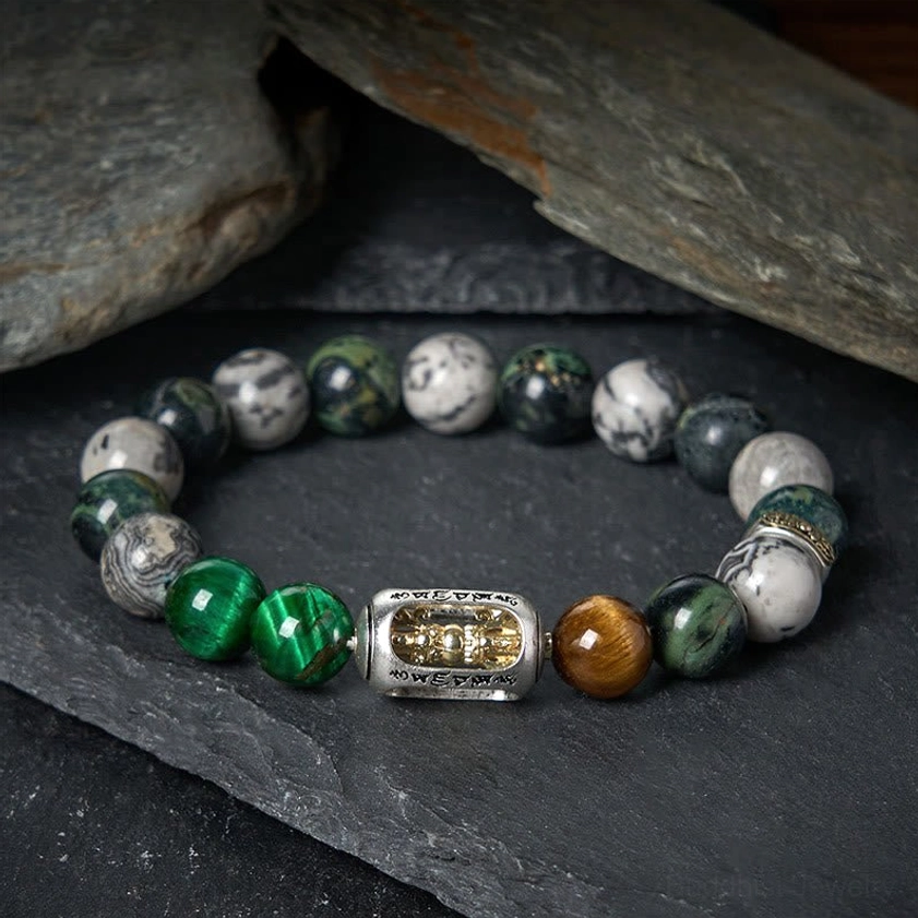Om Mani Padme Hum protection bracelet with mixed natural stone beads including grey jasper, tiger eye, and green tiger eye with engraved Buddhist mantra metal charm on dark background