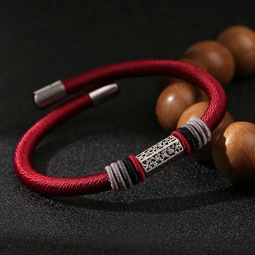 Red string bracelet with 925 sterling silver Om Mani Padme Hum charm, close-up with wooden prayer beads