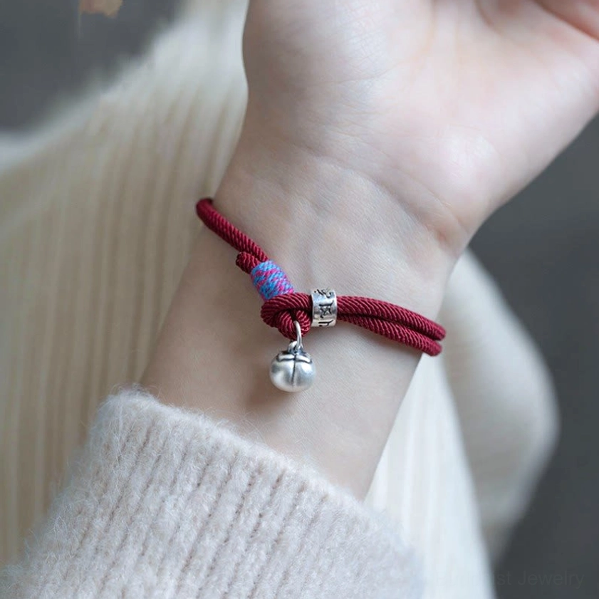 Red Om Mani Padme Hum bracelet worn on human wrist with knit sweater showing everyday styling